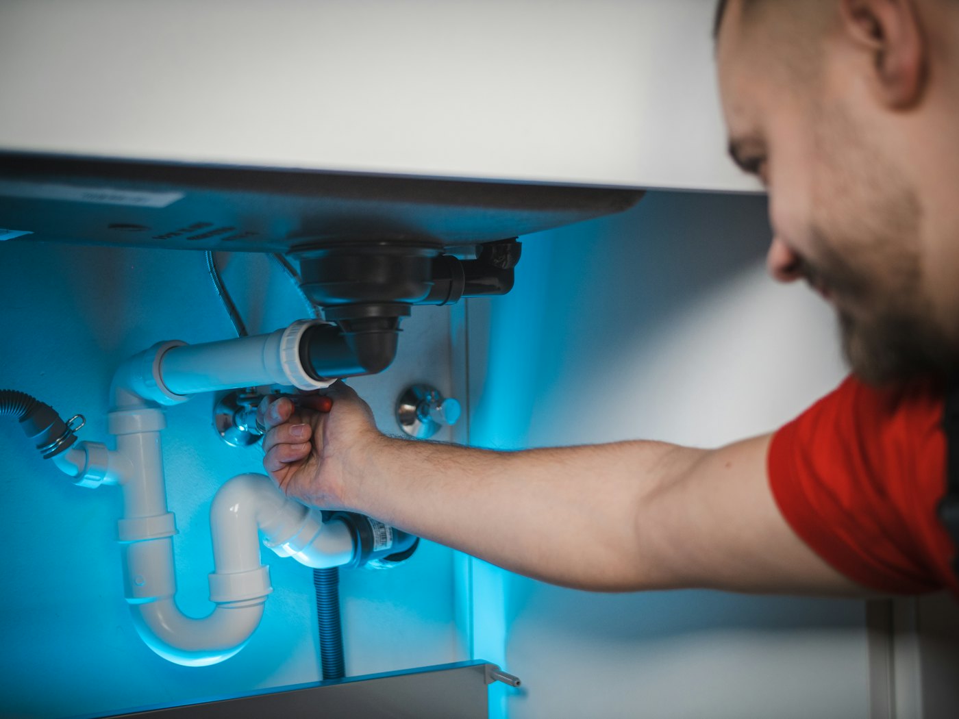 Plumber working on pipes under a sink