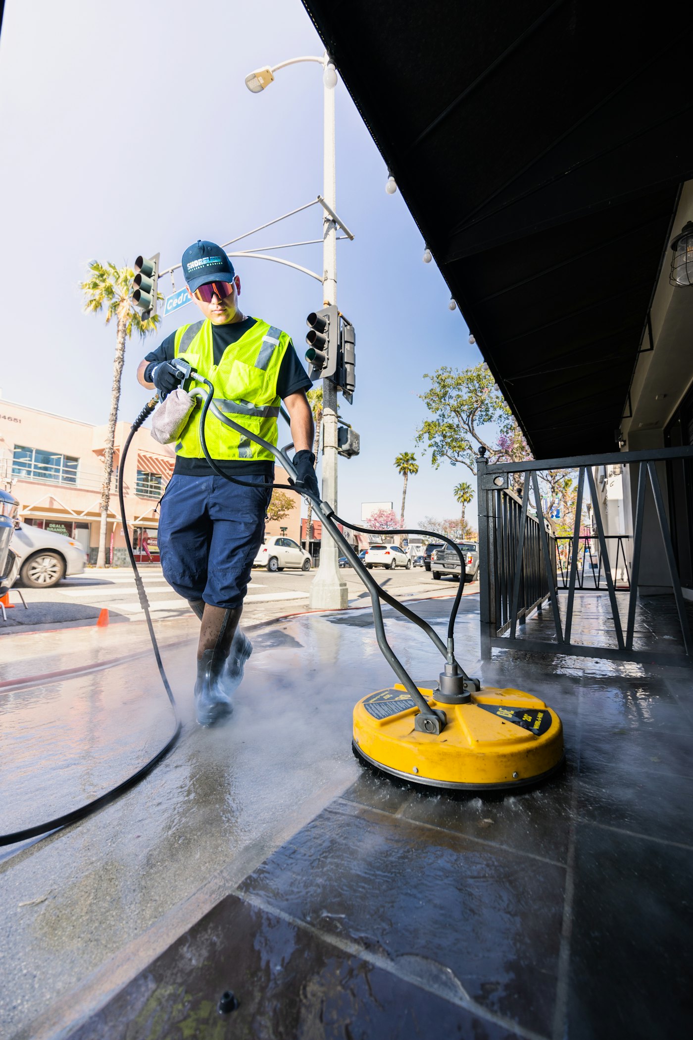 Crew member pressure washing a sidewalk