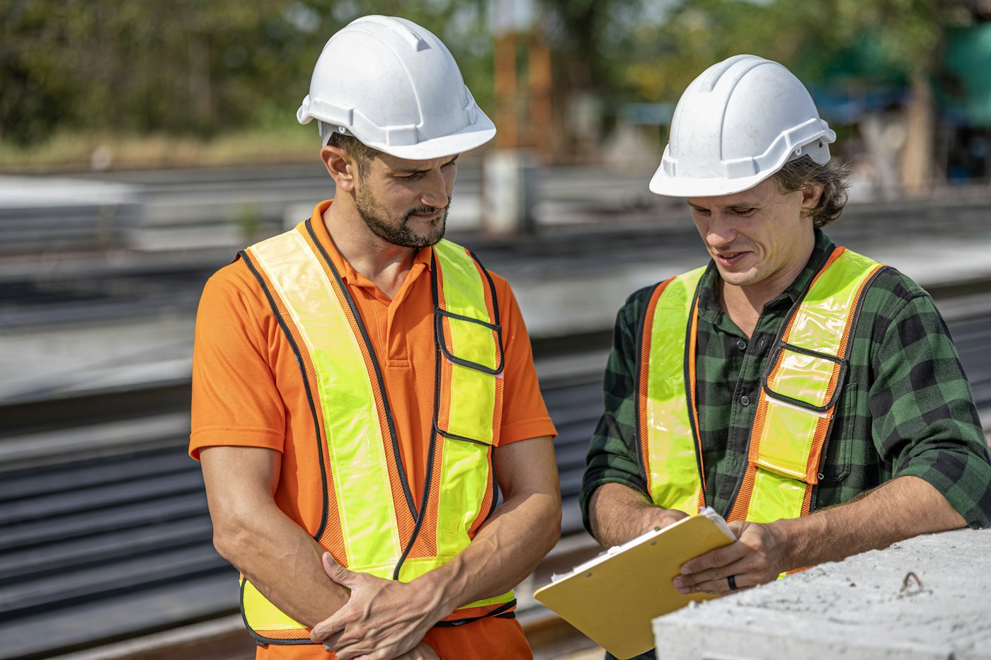 Two workers in hard hats reviewing a site checklist